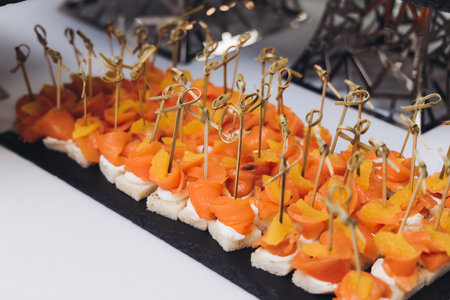 Catering table, beautifully decorated banquet with variety of different food snacks appetizers on Christmas birthday corporate party event or wedding celebration, canape, salad, delicatessen settingの写真素材