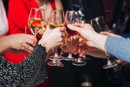 Group of guests celebrate and raise glasses, toasting and cheering with alcohol glasses with wine and champagne in the restaurant on corporate christmas birthday party event or wedding celebrationの写真素材