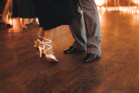 Dancing stiletto shoes of couples dancing traditional latin argentinian dance milonga in the ballroom, tango salsa bachata kizomba lesson in red and purple lights, evening dance school class festivalの写真素材