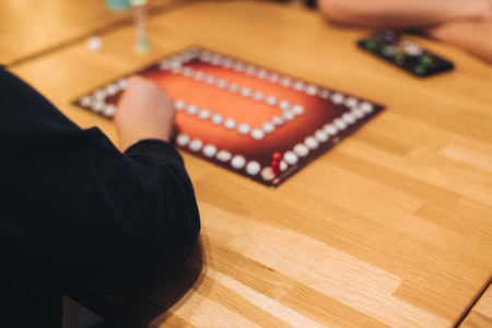 Process of playing tabletop board game on the table, fun with friends and family in room indoors, board game party concept, company group of students adults play board games, roll the dice on game mapの写真素材