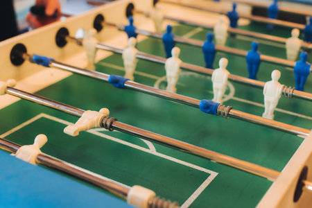 Group of friends playing kicker in a sports bar room, colleagues playing table football, table soccer game in the office, having fun, tabletop football match competition at work, backyard gamesの写真素材