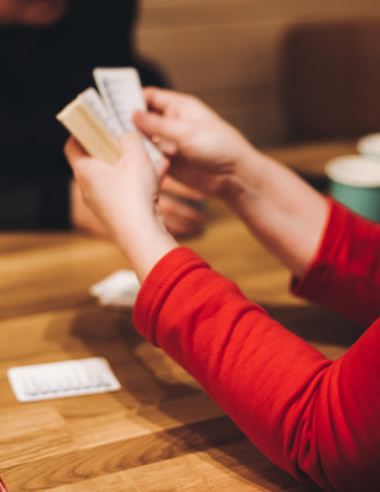 Process of playing tabletop board game on the table, fun with friends and family in room indoors, board game party concept, company group of students adults play board games, roll the dice on game mapの写真素材