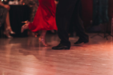 Dancing stiletto shoes of couples dancing traditional latin argentinian dance milonga in the ballroom, tango salsa bachata kizomba lesson in red and purple lights, evening dance school class festivalの写真素材