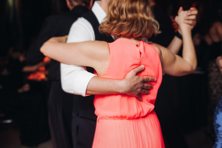 Couples dancing traditional latin argentinian dance milonga in a ballroom, tango salsa bachata kizomba lesson in red and purple lights, performance rehearsal, evening dance school class festivalの写真素材