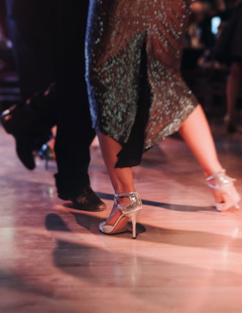 Dancing stiletto shoes of couples dancing traditional latin argentinian dance milonga in the ballroom, tango salsa bachata kizomba lesson in red and purple lights, evening dance school class festivalの写真素材