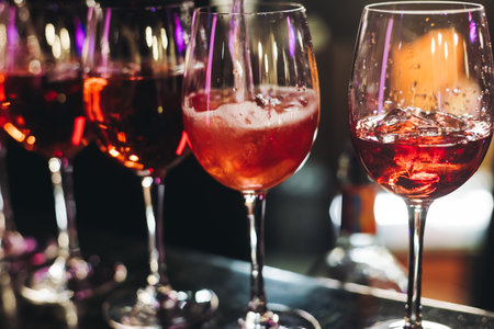 Bartender working, barman mixing and pouring drinks and beverages in a club, beautiful row line of different red colored liquor alcohol cocktails on a party in a bar, catering banquet on eventの写真素材