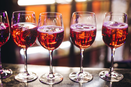 Bartender working, barman mixing and pouring drinks and beverages in a club, beautiful row line of different red colored liquor alcohol cocktails on a party in a bar, catering banquet on eventの写真素材