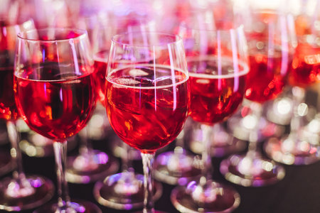 Alcohol setting on catering banquet table, row line of orange red colored aperitif alcohol cocktails on party, negroni, spritz and others on bar counter, selection of liquor beverages on eventの写真素材