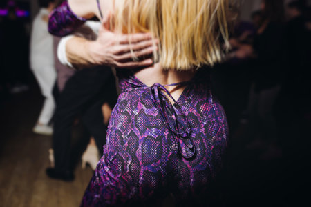 Couples dancing traditional latin argentinian dance milonga in a ballroom, tango salsa bachata kizomba lesson in red and purple lights, performance rehearsal, evening dance school class festivalの写真素材