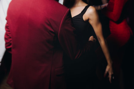 Couples dancing traditional latin argentinian dance milonga in a ballroom, tango salsa bachata kizomba lesson in red and purple lights, performance rehearsal, evening dance school class festivalの写真素材