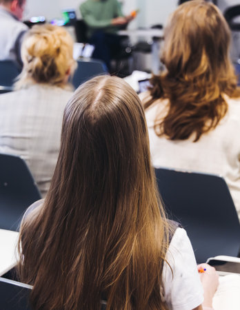 Audience at the modern conference hall listens to panel discussion, people on a congress together listen to speaker on stage at convention, plenary session at business seminar, venue for presentationの写真素材