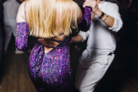 Couples dancing traditional latin argentinian dance milonga in a ballroom, tango salsa bachata kizomba lesson in red and purple lights, performance rehearsal, evening dance school class festivalの写真素材
