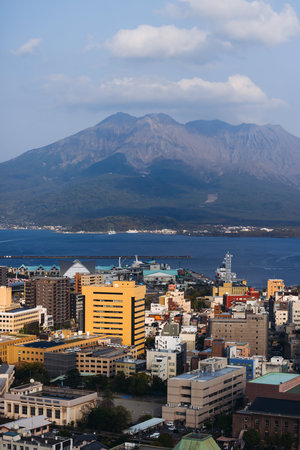 View of Kagoshima city, Japan, Kagoshima prefecture, Kyushu island region, with Sakurajima volcano and Kagoshima bay, seen from Shiroyama park mountain observatory in a spring day with blue skyの写真素材