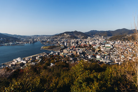 Nagasaki panorama, Japan, beautiful aerial view, with city skyline, port and mountains, seen from Nabekammuri mount, in a spring sunny day with a blue sky, Nagasaki prefecture, Kyushu island regionの写真素材
