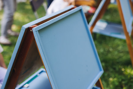 Kids drawing at plein air, group class of talented children with painting easel and wooden canvas during lesson of watercolor painting outdoors in summer, art school class for young teen artistsの写真素材