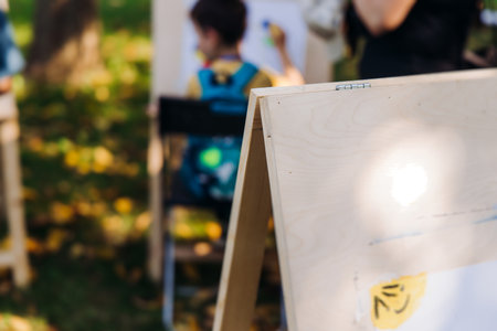 Kids drawing at plein air, group class of talented children with painting easel and wooden canvas during lesson of watercolor painting outdoors in summer, art school class for young teen artistsの写真素材