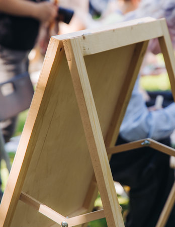 Kids drawing at plein air, group class of talented children with painting easel and wooden canvas during lesson of watercolor painting outdoors in summer, art school class for young teen artistsの写真素材