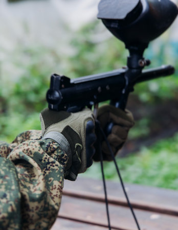 Paintball game, team in camouflage protective uniform with paintball guns and ammunition, strikeball...