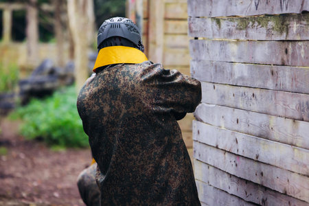 Paintball game, team in camouflage protective uniform with paintball guns and ammunition, strikeball arena battlefield, paintballer aiming and shooting at opponents, airsoft players match tournamentの写真素材