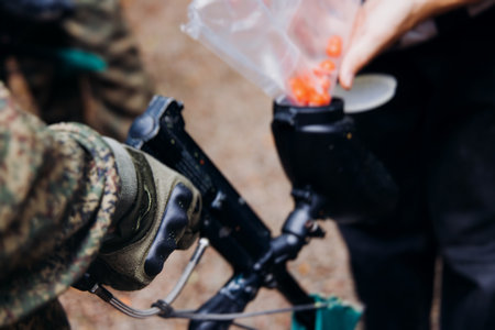 Paintball game, team in camouflage protective uniform with paintball guns and ammunition, strikeball arena battlefield, paintballer aiming and shooting at opponents, airsoft players match tournamentの写真素材