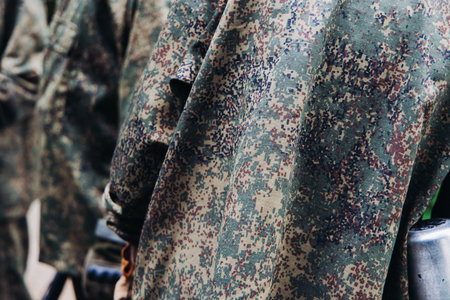 Paintball game, team in camouflage protective uniform with paintball guns and ammunition, strikeball arena battlefield, paintballer aiming and shooting at opponents, airsoft players match tournamentの写真素材