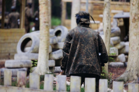 Paintball game, team in camouflage protective uniform with paintball guns and ammunition, strikeball arena battlefield, paintballer aiming and shooting at opponents, airsoft players match tournamentの写真素材