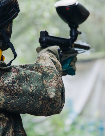 Paintball game, team in camouflage protective uniform with paintball guns and ammunition, strikeball arena battlefield, paintballer aiming and shooting at opponents, airsoft players match tournamentの写真素材