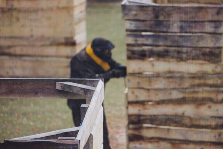 Paintball game, team in camouflage protective uniform with paintball guns and ammunition, strikeball arena battlefield, paintballer aiming and shooting at opponents, airsoft players match tournamentの写真素材