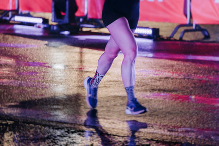 Night marathon runners crowd in the rain, sportsmen participants start running the half-marathon in...