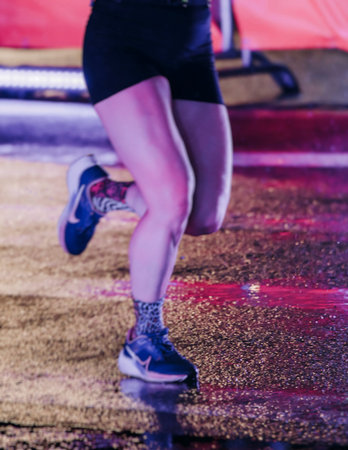 Night marathon runners crowd in the rain, sportsmen participants start running the half-marathon in...