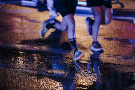 Night marathon runners crowd in the rain, sportsmen participants start running the half-marathon in...