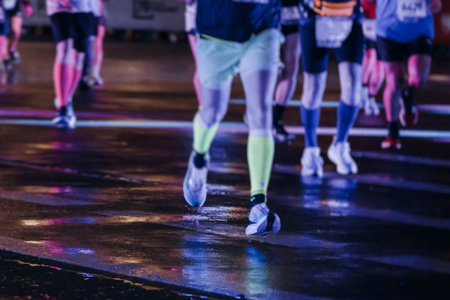 Night marathon runners crowd in the rain, sportsmen participants start running the half-marathon in...