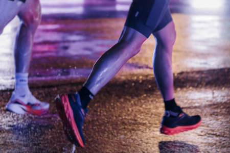 Night marathon runners crowd in the rain, sportsmen participants start running the half-marathon in...