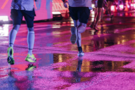 Night marathon runners crowd in the rain, sportsmen participants start running the half-marathon in...