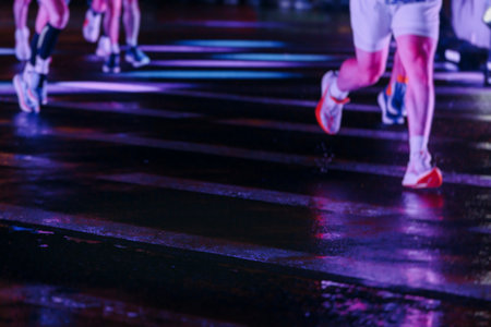 Night marathon runners crowd in the rain, sportsmen participants start running the half-marathon in...