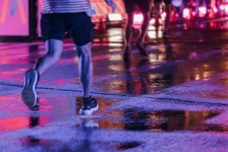Night marathon runners crowd in the rain, sportsmen participants start running the half-marathon in...