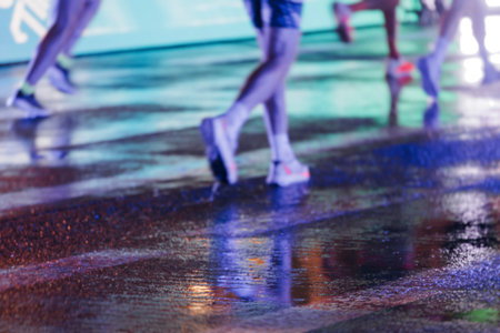Night marathon runners crowd in the rain, sportsmen participants start running the half-marathon in...