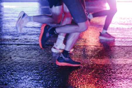 Night marathon runners crowd in the rain, sportsmen participants start running the half-marathon in...