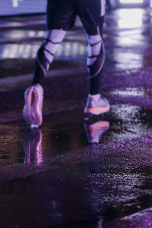 Night marathon runners crowd in the rain, sportsmen participants start running the half-marathon in...