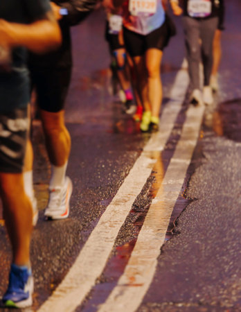 Night marathon runners crowd in the rain, sportsmen participants start running the half-marathon in...
