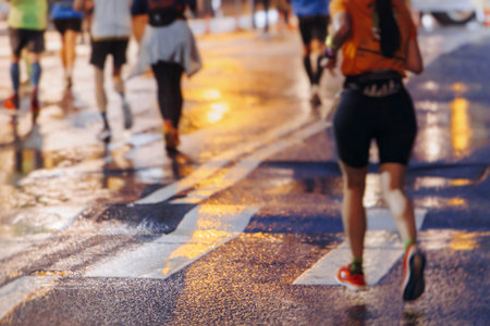 Night marathon runners crowd in the rain, sportsmen participants start running the half-marathon in...