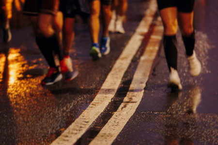 Night marathon runners crowd in the rain, sportsmen participants start running the half-marathon in...