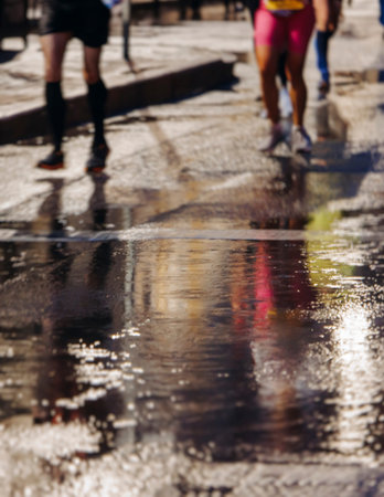 Night marathon runners crowd in the rain, sportsmen participants start running the half-marathon in the city streets with night lighting and illumination, group crowd of sportswomen joggers in motionの写真素材