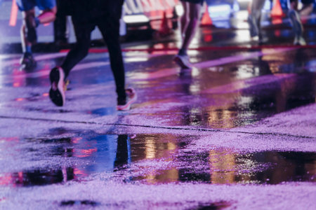 Night marathon runners crowd in the rain, sportsmen participants start running the half-marathon in...