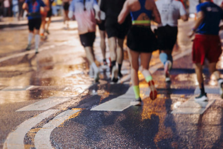 Night marathon runners crowd in the rain, sportsmen participants start running the half-marathon in...