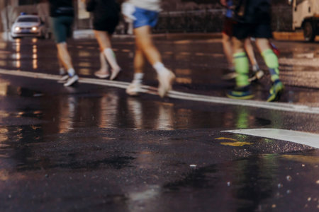 Night marathon runners crowd in the rain, sportsmen participants start running the half-marathon in...