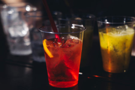 Barman mixing liquor beverages and alcohol drinks in plastic cups, bartender working, beautiful row...