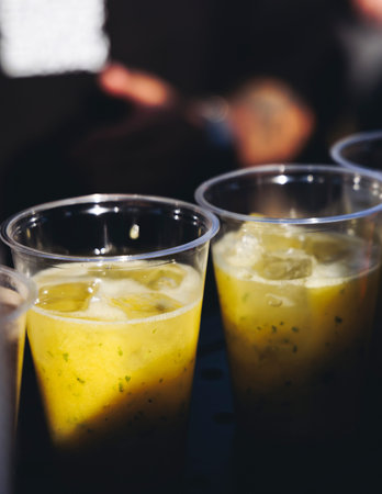 Barman mixing liquor beverages and alcohol drinks in plastic cups, bartender working, beautiful row...