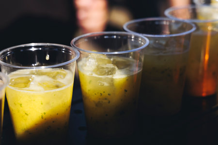Barman mixing liquor beverages and alcohol drinks in plastic cups, bartender working, beautiful row...
