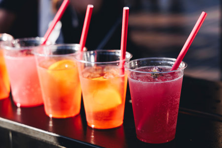Barman mixing liquor beverages and alcohol drinks in plastic cups, bartender working, beautiful row...